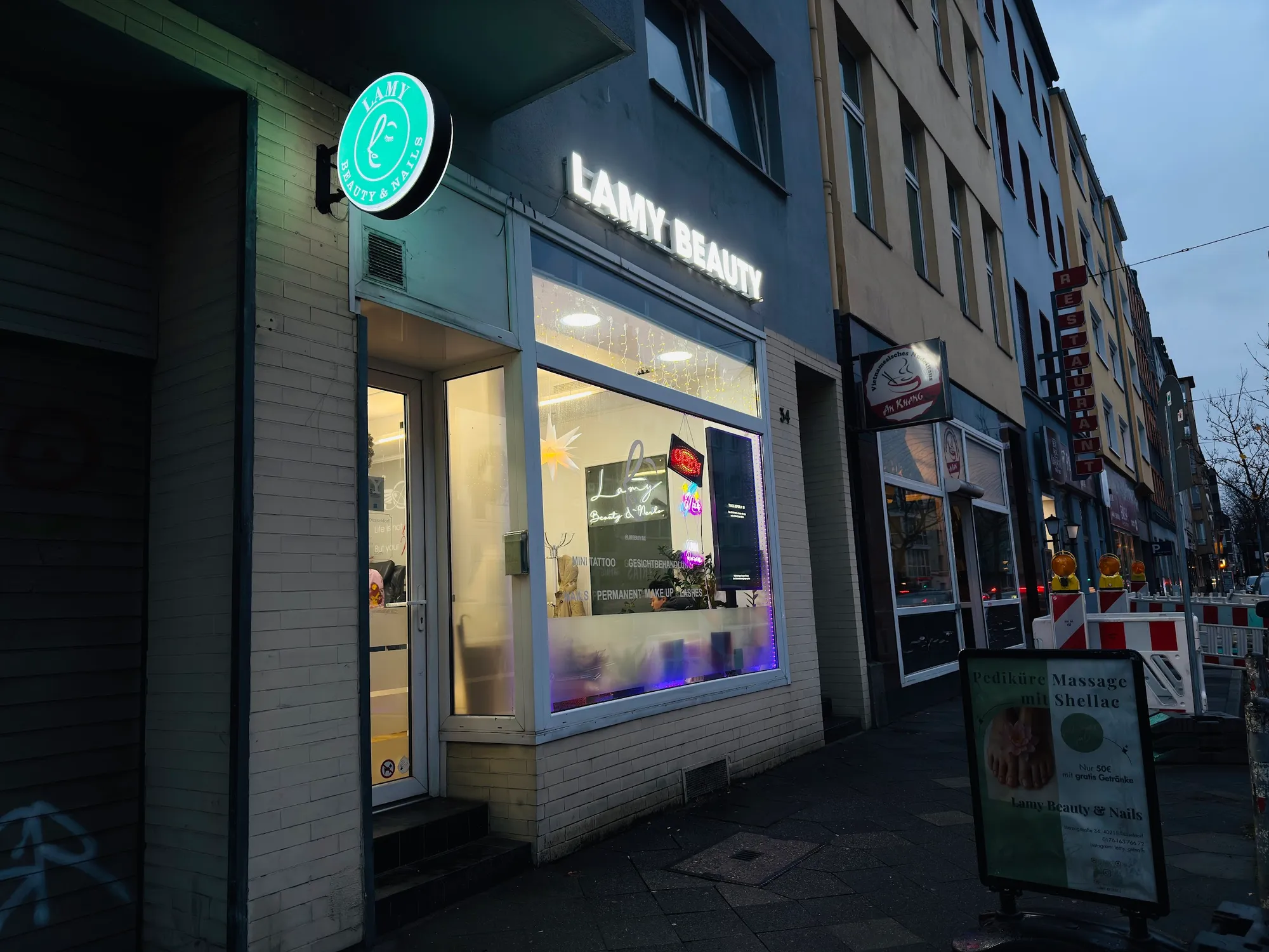 Ladenfront von Lamy Beauty an der Herzogstraße am Abend, mit beleuchtetem Schriftzug und mintfarbenem Rundschild